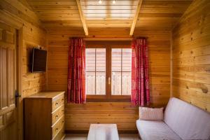 Habitación de madera con sofá y ventana en Aranjuez Camping & Bungalows, en Aranjuez
