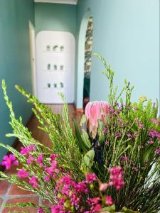 un jarrón lleno de flores rosas en una mesa en Rondebosch Cottage, en Ciudad del Cabo