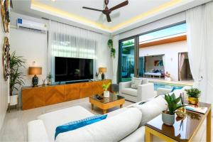 sala de estar con sofá blanco y TV en Villa Mimosa 1, Splendid 4 Bedroom Master Ensuite en Phuket
