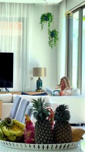 a woman sitting in a living room with a tray of fruit at Villa Mimosa 1, Splendid 4 Bedroom Master Ensuite in Phuket Town