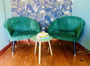 dos sillas verdes sentadas junto a una mesa con un libro en Rondebosch Cottage, en Ciudad del Cabo