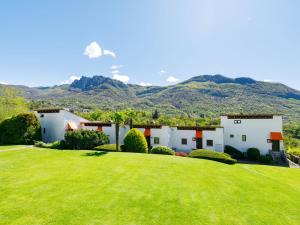 a house with a green yard with mountains in the background at Apartment Villaggio Sureggio - App- C1 by Interhome in Lugaggia
