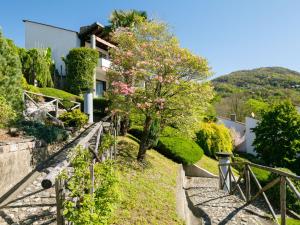 a house with a tree with pink flowers on a hill at Apartment Villaggio Sureggio - App- C1 by Interhome in Lugaggia