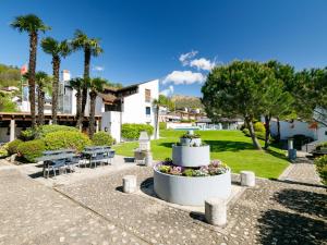 a park with a fountain and tables and palm trees at Apartment Villaggio Sureggio - App- C1 by Interhome in Lugaggia