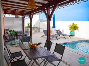 a patio with a table and chairs next to a pool at Villa Noëlyne in Le Robert