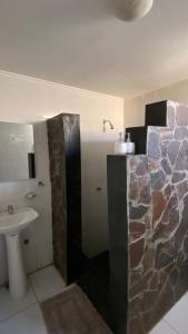 uma casa de banho com um chuveiro de pedra e um lavatório. em San Pedro Domos em San Pedro de Atacama