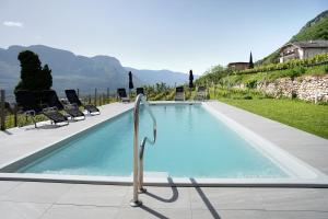 a large swimming pool with chairs at Bacchushof Apartment Cabernet in Termeno