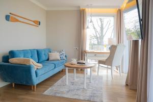 a living room with a blue couch and a table at Szerokie Wody Sea & Sand Ustka in Ustka