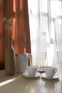 una mesa con dos tazas y una cafetera y un jarrón en Madera Hotel, en Tiflis