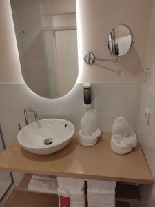 La salle de bains est pourvue d'un lavabo, d'un miroir et de serviettes. dans l'établissement Sol i Vida Hotel - Adults Only, à Porto Cristo