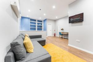 ein Wohnzimmer mit einem grauen Sofa und einem TV in der Unterkunft GuestReady - The New Lazuli Flat in Porto