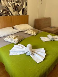 two beds with white towels on a green blanket at 4 Sisters Apartments in Gradac