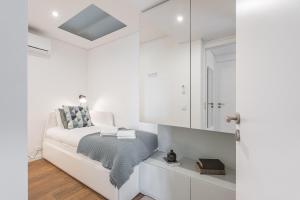 - une chambre blanche avec un lit et un miroir dans l'établissement GuestReady - Riverview Douro Terrace, à Vila Nova de Gaia