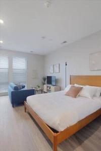 a bedroom with a large bed and a blue chair at CozySuites Spacious SDO, Lawrenceville in Pittsburgh +27 photos
