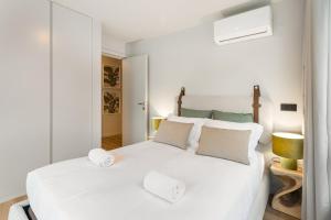 a white bedroom with a large white bed with two pillows at GuestReady - Grey Roof in Vila Nova de Gaia in Santo Ovídio