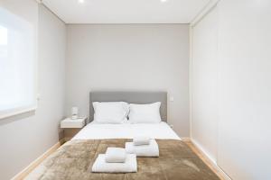 um quarto branco com uma cama e 2 toalhas em GuestReady - Ideal Getaway minutes from Porto em Gondomar