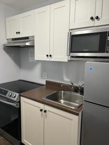uma cozinha com armários brancos, um lavatório e um micro-ondas em East End Suite em Eastern Passage