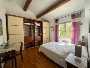um quarto com uma cama, uma secretária e uma janela em La Boissetane, maison provençale avec piscine et jardin, au pied du Luberon em Saint-Martin-de-Castillon