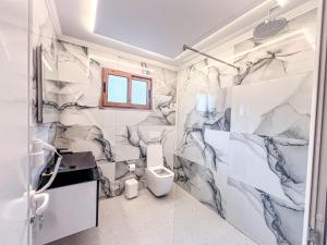 baño con paredes de mármol blanco y gris y aseo en Logu i Harushave en Theth