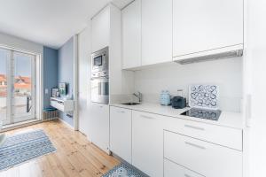 uma cozinha branca com armários brancos e uma janela em GuestReady - The Other Side no Porto