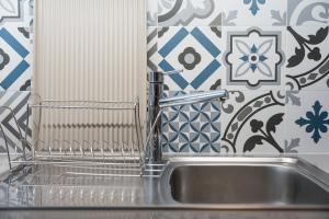 a stainless steel sink in a kitchen with blue and white tiles at GuestReady - Well furnished studio in Porto. in Porto