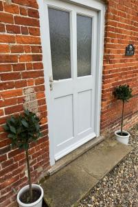 two potted plants in front of a door at Cosy Cottage in the Norfolk Countryside in Whissonsett