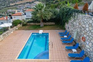 a swimming pool with blue chairs next to a wall at Villa Sunlights Bali in Balíon
