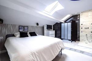 - une chambre avec un grand lit blanc et une lucarne dans l'établissement Loft Évasion luxe Jacuzzi, à Reims