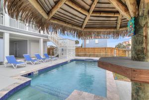 a swimming pool with blue chairs and a house at Casa De Coconuts in Padre Island