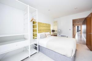 a bedroom with a white bed and white shelves at Austin David Executive ExCeL in London