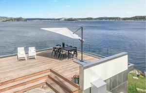 eine Holzterrasse mit einem Tisch und einem weißen Regenschirm in der Unterkunft Cozy Home In Stabbestad With House Sea View in Stabbestad