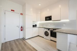 a kitchen with white cabinets and a washer and dryer at GuestReady - Matosinhos Deluxe near the beach in Matosinhos