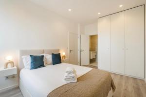 a white bedroom with a large bed with blue pillows at GuestReady - Matosinhos Deluxe near the beach in Matosinhos