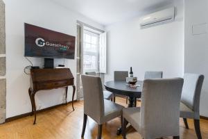 uma sala de jantar com mesa e cadeiras e uma TV em GuestReady - Modern Duplex, Neo-Classical Building no Porto