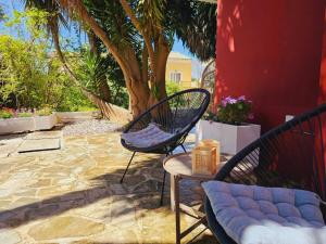 um pátio com duas cadeiras, uma mesa e uma árvore em Corfu Dream Holidays Villas em Kanoni