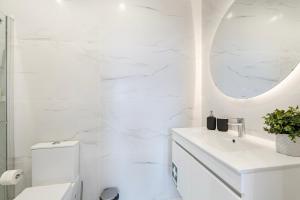 een witte badkamer met een wastafel en een spiegel bij GuestReady - Oz's Place Haven in Matosinhos