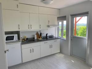 a white kitchen with white cabinets and a window at Gwiezdna łąka, domki kontenerowe in Borowa