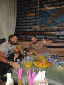 grupa mężczyzn siedzących przy stole z jedzeniem w obiekcie Petra Anas House w mieście Wadi Musa