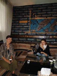 two women sitting on chairs in a room with a wooden wall at Petra Anas House in Wadi Musa