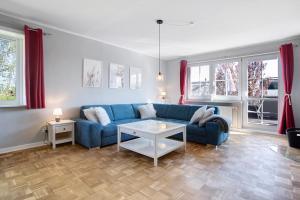 - un salon avec un canapé bleu et quelques fenêtres dans l'établissement Rügenferienhaus komplett, à Schaprode
