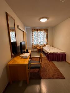 een kleine kamer met een bed, een bureau en een televisie bij Grand Hostel Imatra in Imatra