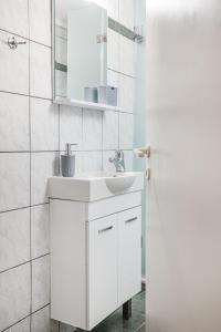 a white bathroom with a sink and a mirror at Sunrise Apartment in Heraklio