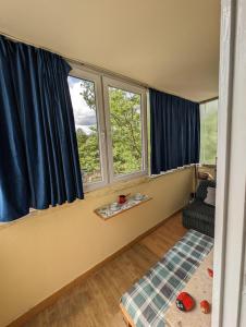 ein Wohnzimmer mit 2 Fenstern und blauen Vorhängen in der Unterkunft Dwell well in Mostar in Mostar