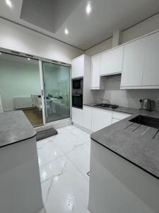 a kitchen with white cabinets and a large window at Elegant living, 3 bedroom modern house in London