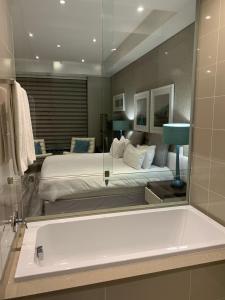 een badkamer met een bad en een bed in een kamer bij Sandton Skye Apartment in Johannesburg