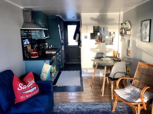 uma sala de estar com um sofá azul e uma cozinha em Brighton Water Cabin - a unique floating holiday home em Brighton & Hove