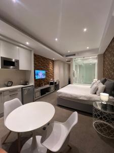 een slaapkamer met een bed en een witte tafel en stoelen bij Sandton Skye Apartment in Johannesburg