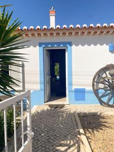 a small white house with a door and a wheel at Villa Alba in Aljezur