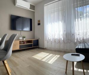 uma sala de estar com uma televisão e uma mesa e cadeiras em Homestead - Domačija - Nabergoj em Podnanos