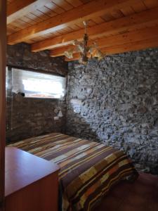 a bedroom with a bed in a stone wall at CASA TOMASIN 